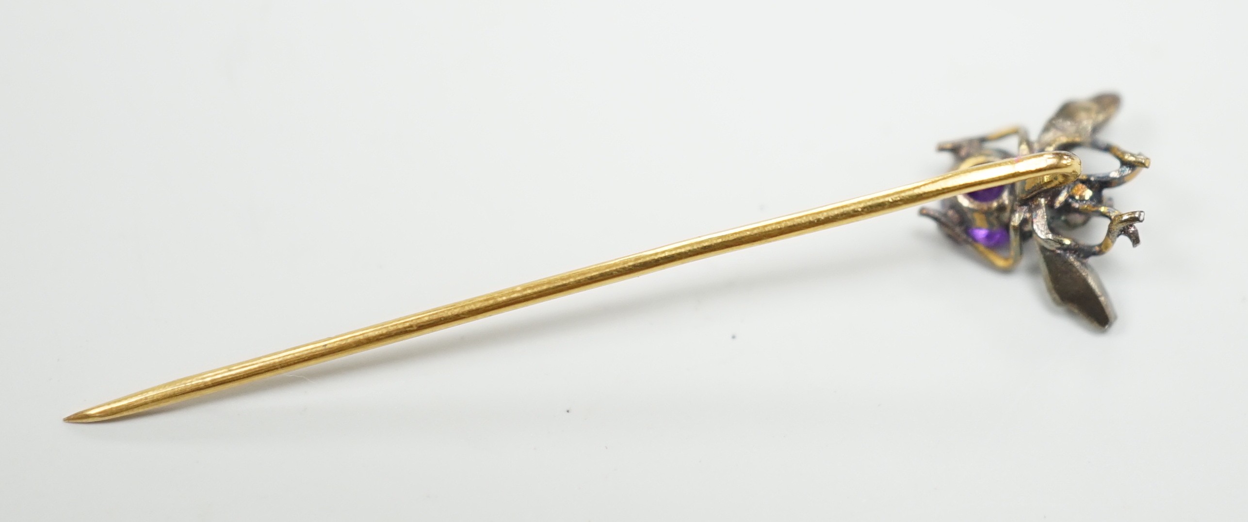 An early 20th century yellow and white metal amethyst and seed pearl set bug stick pin, 4mm, gross weight 0.6 grams.